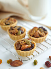 Appetizing tartlets stuffed with hazelnuts walnuts covered with a layer of liquid caramel. Homemade mini tart, selective focus.