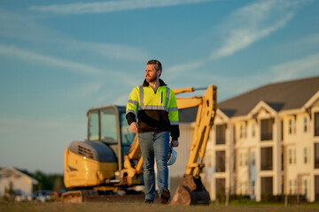 Builder in a construction site. Builder with excavator ready to build new house. Construction builder wear building uniform on excavation truck digging, builder with buildings construction background.