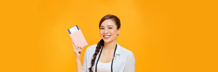 woman over isolated yellow background happy in vacation with passport and plane tickets