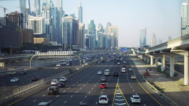 The active Dubai's Sheikh Zayed Road at dusk, with the metro passing beside the iconic skyline and bustling vehicles.