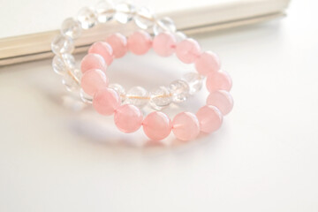 Rose quartz crystal bracelet and clear quartz bracelet on the table. Pink stone for healing and...