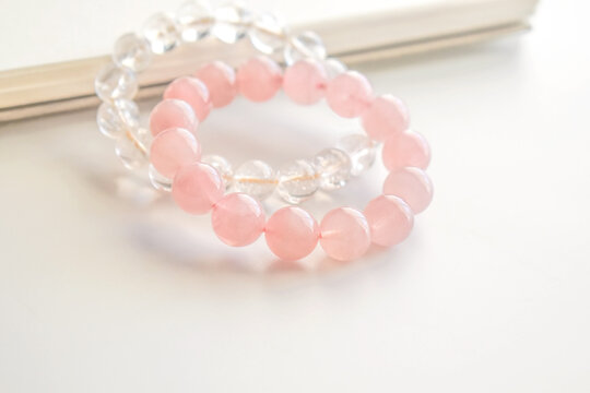 Rose quartz crystal bracelet and clear quartz bracelet on the table. Pink stone for healing and protection. Jewellery fashion design.  