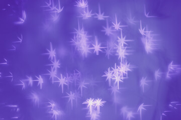 Bokeh as lights purple stars on lavender color background, happy winter holiday wallpaper with blurred pattern. Happy Christmas or New Year abstract magic light aesthetic photo, blurred effect