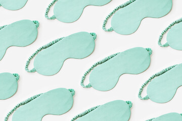 Minimal pattern from silk sleep masks on white light background. Mint colored fashion eye masks for best sleepers, for travel, comfort rest. Night time and sleep concept, flat lay composition
