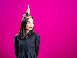 Portrait of an Asian Indonesian woman wearing a Halloween-themed costume with a witch hat, standing...