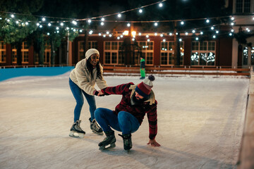 Biracial couple learning to skate at outdoors rink