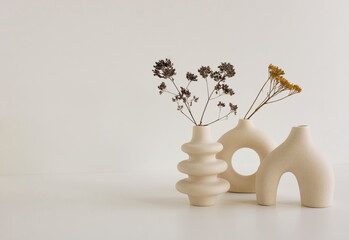 Modern beige ceramic vases set with dry  grass on white table near white  wall.Copy space,  Scandinavian interior accessories.