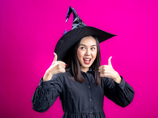 Portrait of an Asian Indonesian woman wearing a Halloween-themed costume with a witch hat,...