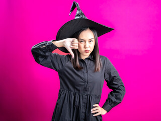 Portrait of an Asian Indonesian woman wearing a Halloween-themed costume with a witch hat,...