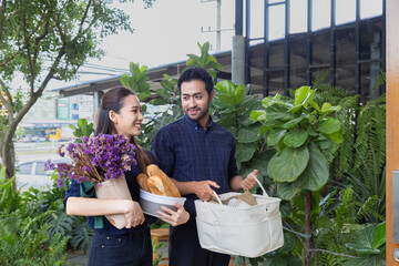 Asian business couple carrying goods and bread for opens a small cafe together, husband and wife...