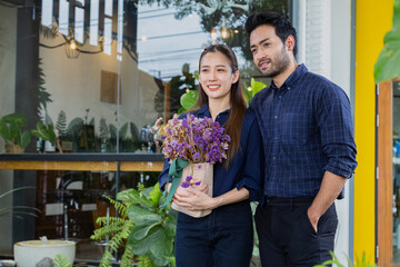 Asian successful couple stands in front of their cafe. Husband and wife open small coffee shop...