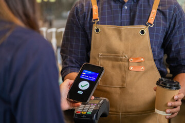 Close up baristas or cashier worker hold payment machine accept credit card cashless transaction from customer, Smart employee hands payment scanners to customers in cafe shop, pay for morning coffee. - obrazy, fototapety, plakaty