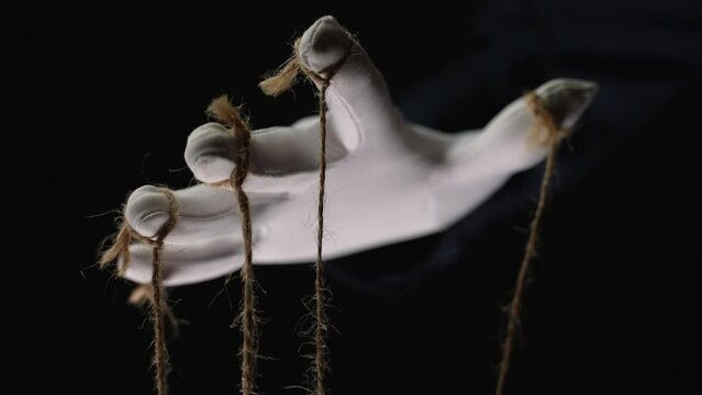Manipulator hands in white gloves with ropes on fingers