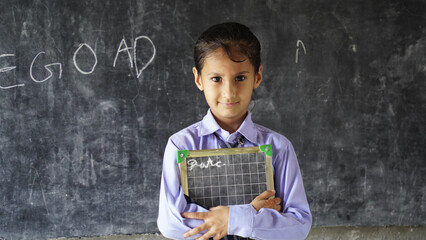 Happy Cute Indian, Asian Pretty elementary school child or kid in uniform raising hand in classroom. Education concept.