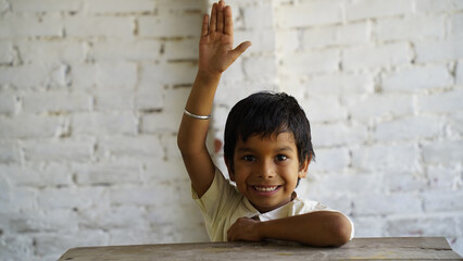 Happy Cute Indian, Asian Pretty elementary school child or kid in uniform raising hand in classroom. Education concept.