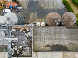 An impressive aerial perspective showcasing industrial silos standing next to a factory building, illustrating the industrial infrastructure and manufacturing operations from above. Aerial View of