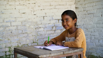 Fototapeta na wymiar Indian school child sitting at desk in classroom with notebooks writing test Elementary school, Education concept.