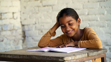 Indian school child sitting at desk in classroom with notebooks writing test Elementary school,...
