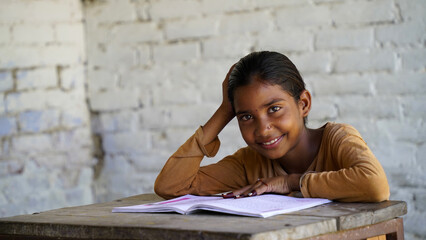 Indian school child sitting at desk in classroom with notebooks writing test Elementary school,...