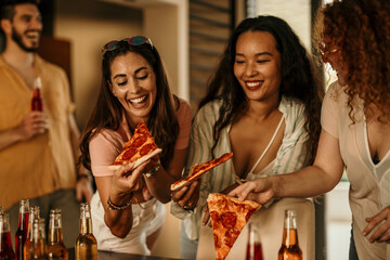 Diverse group of friends enjoying a lively day in a vibrant house party, savoring delicious pizza slices and refreshing beverages