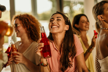 Smiling woman and her friends enjoy a lively day in a vibrant house party, savoring delicious pizza slices and refreshing beverages. 