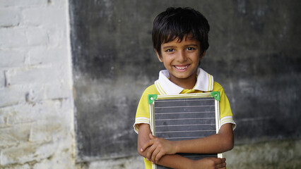 Rural School boy holding slate with English alphabet. Indian child writing A B C D alphabet on...