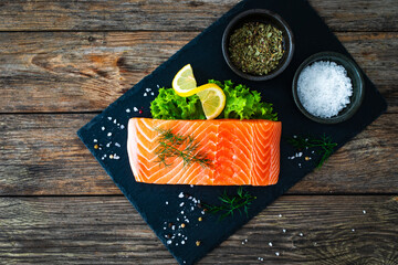 Fresh raw salmon steak with salt and fresh vegetables on wooden background
 - Powered by Adobe