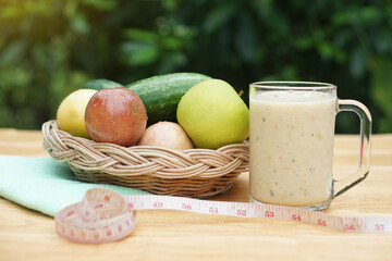 Glass of smoothie mixed fruits, basket of fresh fruits and measuring tape. Concept, healthy beverage for health. Well being and weight loss menu. Homemade refreshing fruit drinks. High fibers, detox. 