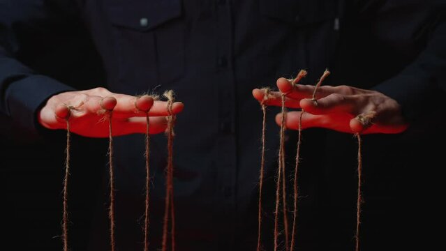 Manipulator hands with ropes on fingers. Black background