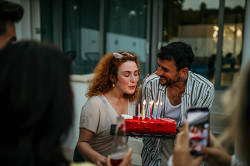 A group of beaming friends comes together to commemorate a special birthday, the air filled with excitement and merriment