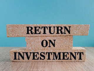 Return on investment concept. ROI text written on brick blocks. Beautiful blue background, wooden...