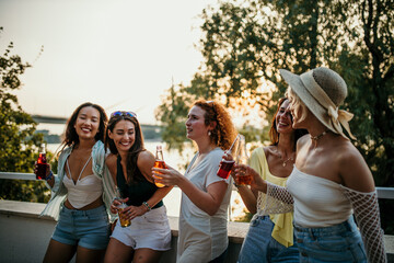 A group of girlfriends cherishing the moment with drinks in hand, enveloped by the beauty of a...