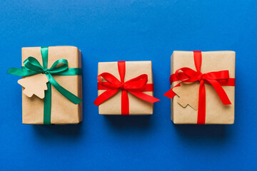 wrapped christmas or other holiday handmade present in paper with colored ribbon. Present box, decoration of gift on colourfull table, top view with copy space