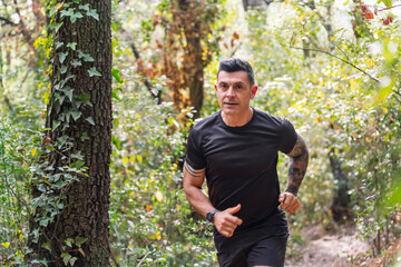horizontal portrait of a man practicing trail running in the forest, concept of sport in nature and healthy lifestyle, copy space for text