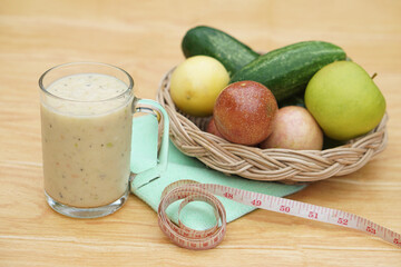 Glass of smoothie mixed fruits, basket of fresh fruits and measuring tape. Concept, healthy...