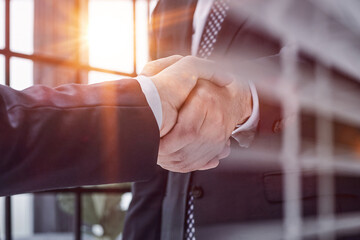 executives shaking hands in front of their manager and a colleague