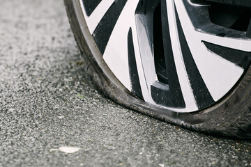 Fototapeta premium Roadside Assistance Needed for a Flat Tire. Closeup of the car flat tire
