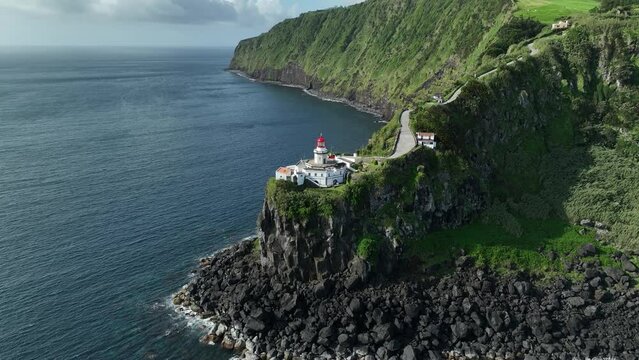 Epic setting of Farol Ponta do Arnel lighthouse on Sao Miguel coastline. Aerial