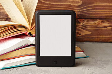Digital tablet and stack of hardcover books against wooden background