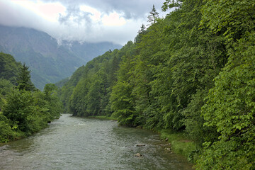 Traun river flowing through the mountains, Salzkammergut region in the Austrian Alps. Beautiful foggy and cloudy landscape with river and mountains in summer. Natural colorful background.