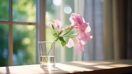A delicate sweet pea  a glass cup on ceramic table