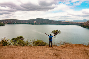 View of a tourist with arms raised at Lake Chala at Kenya Tanzania border