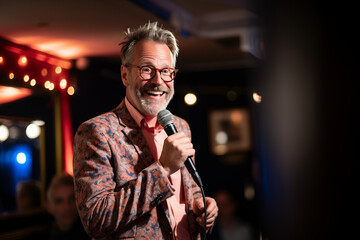 Old Caucasian male comedian performing his stand-up monologue on a stage of a small venue