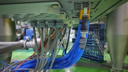 A bunch cable and hose under machine control panel in production room of factory