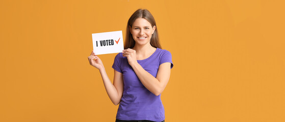 Young woman holding paper with text I VOTED on orange background
