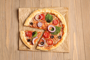 Baking paper of tasty pizza with basil and tomatoes on wooden background