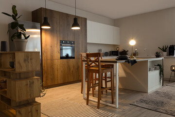 Interior of modern kitchen with glowing lamps and laptop on island table