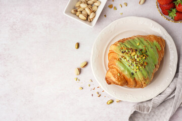 Plate with sweet croissant and pistachio nuts on white background