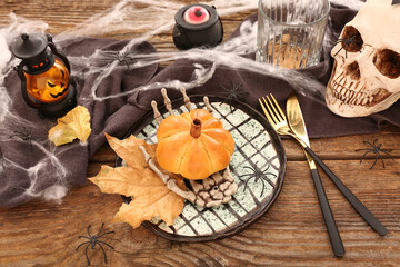Halloween table setting with tasty pumpkin shaped bun on wooden background