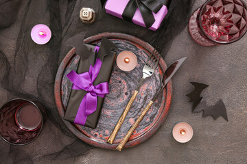 Halloween table setting with gift boxes and burning candles on dark background, closeup